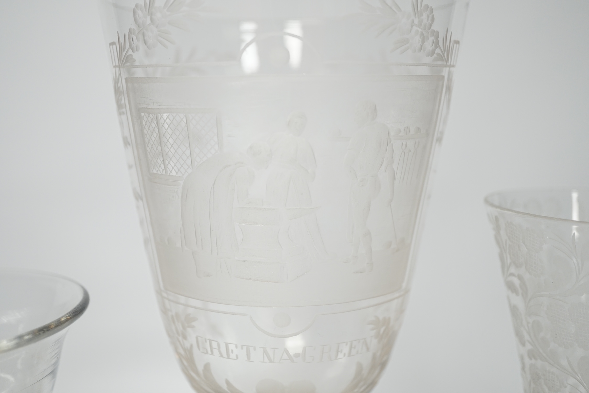 An 18th century sweetmeat glass, a 19th century large wheel engraved ‘Gretna Green’ goblet and a similar floral engraved glass, tallest 23cm. Condition good